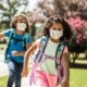 two-girls-running-to-school-wearing-backpacks-and-masks